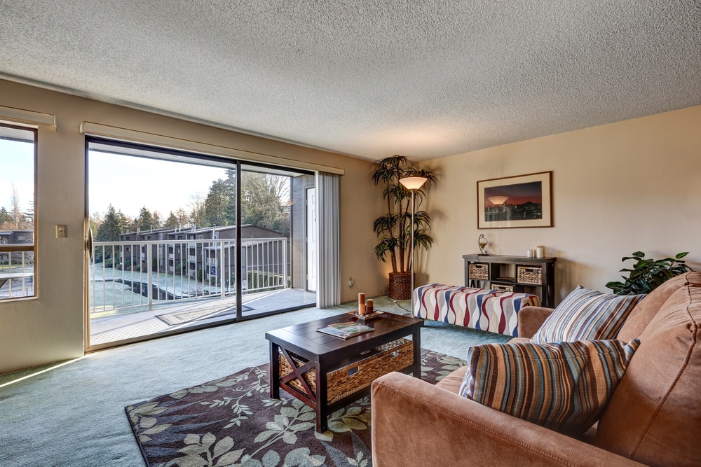 Modern living room with a brown sofa, striped cushions, and large sliding doors showcasing an outdoor view